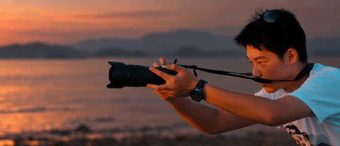 Chen Jing holding a camera toward the evening landscape